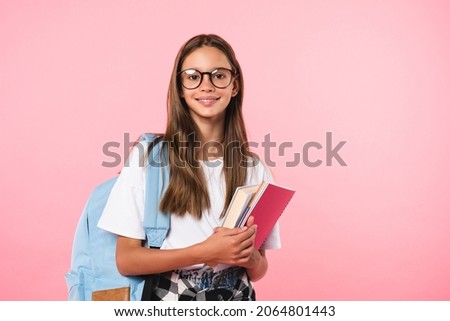 Smiling active excellent best student schoolgirl holding books and copybooks going to school wearing glasses and bag isolated in pink background Royalty-Free Stock Photo #2064801443