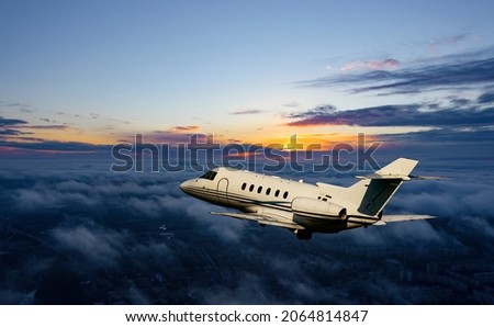 Private airplane jetliner flying above clouds in beautiful sunset light. Travel and business concept. Backside view Royalty-Free Stock Photo #2064814847