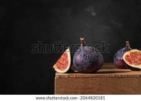 Ripe figs in drops of rain, splashes of rain against a dark background. Close-up, selective focus
