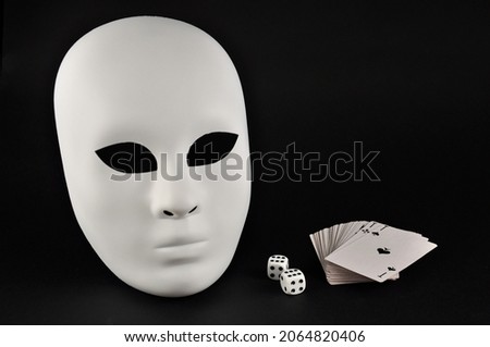 White theatrical mask, playing dice and playing cards