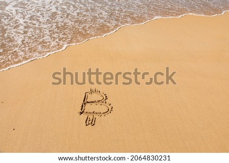 Image of icon bitcoin cryptocurrency on golden sand with sea water background. Concept freelance, stock exchange BTC sign hand written at sandy beach. Unstable rise and fall of concept, top view