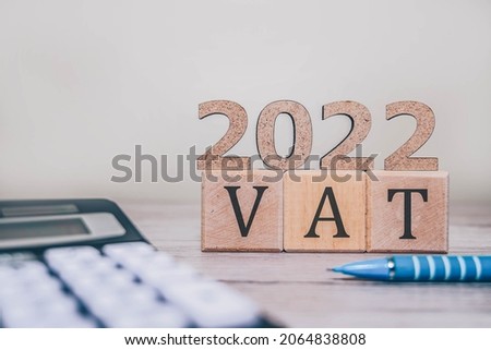 VAT 2022 on wooden cubes, calculator and a pen on a wooden table. VAT 2022 - phrase from wooden blocks with letters, VAT 2022 concept Royalty-Free Stock Photo #2064838808