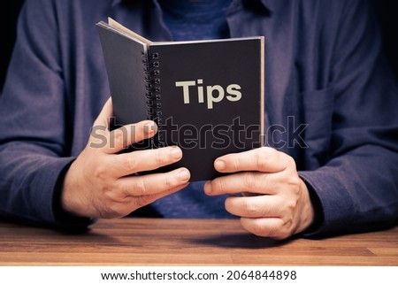 Closeup man is holding and reading the Tips Book, helpful tips concept