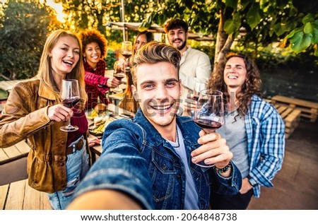 Multiracial friends group taking selfie at barbecue dinner time - Young people chilling outside eating and drinking red wine on patio terrace house - Food and youth friendship concept