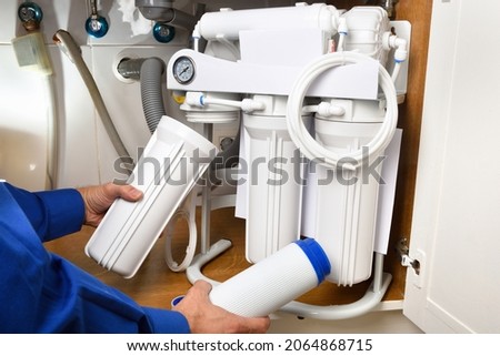 Technician installing reverse osmosis equipment under the sink close up. Front view. Horizontal composition. Royalty-Free Stock Photo #2064868715