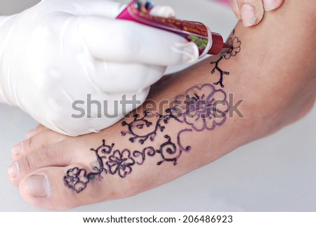 Hand drawing henna art on a foot with white background