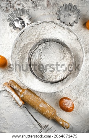 Egg, sieve and rolling pin on flour. Top view. On a white background. 