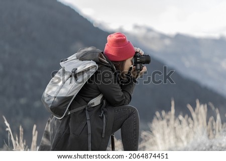 a young woman taking pictures in the mountains