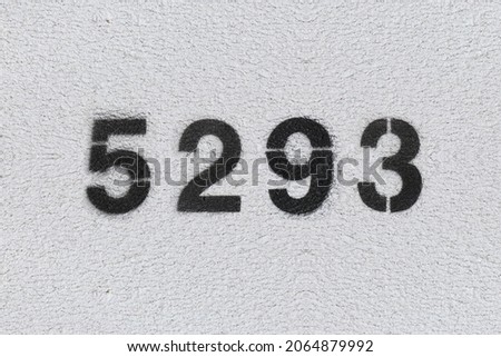 Black Number 5293 on the white wall. Spray paint. Number five thousand two hundred ninety three.