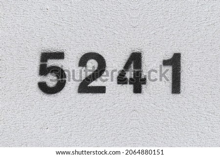 Black Number 5241 on the white wall. Spray paint. Number five thousand two hundred and forty one.