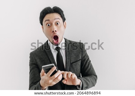 Wow and surprised face of Asian businessman use trade application on the phone.