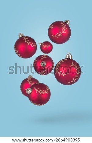 Red Christmas ornaments flying on blue background. Happy holidays. New year minimal concept. Christmas minimal idea.