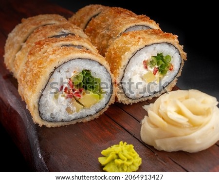 Sliced sushi roll is a traditional Japanese dish. Served on a wooden board with ginger and wasabi paste