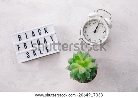 Black friday sale word written on lightbox, plant succulent, white alarm on light background. Flat lay, top view
