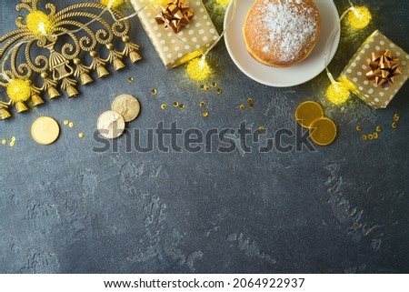 Jewish holiday Hanukkah concept with traditional donuts, menorah and gift box on dark background. Top view with copy space