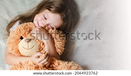 Little Girl hugs her favorite toy. This is a big teddy bear. Love and tenderness. Happy childhood concept. High quality photo. A gift for a birthday or other holiday.  Royalty-Free Stock Photo #2064923762