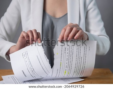 Torn contract in hands. Terminated agreement concept. Ripping paper document and breaching rules. Royalty-Free Stock Photo #2064929726