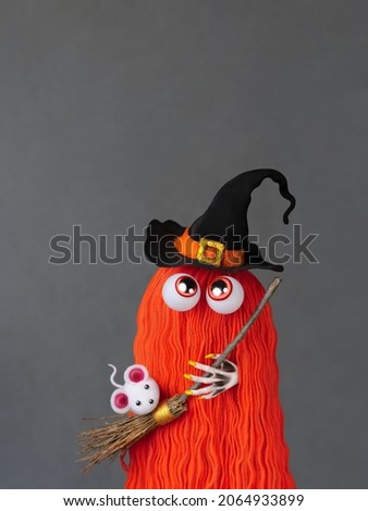 Red haired witch monster in a witch hat with a broom and a white mouse