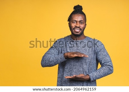 Portrait of african american black man hanging something blank isolated over yellow background. 