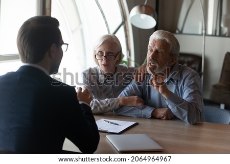Dishonest contractor. Angry elderly couple sit at broker manager office demand compensation for breach of contract bad service. Annoyed mature spouses scam victims complain lawyer on commercial fraud Royalty-Free Stock Photo #2064964967