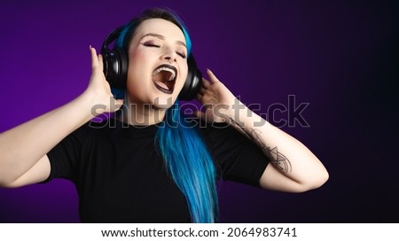 Large banner Woman in black friday, shopping, expressions, with headphones listening to music and dancing, blue hair, copy space, black background, neon style for websites, billboards and boards