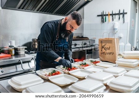 Food in disposable dishes ready for delivery. The chef prepares food in the restaurant and packs it in disposable lunch boxes. Royalty-Free Stock Photo #2064990659