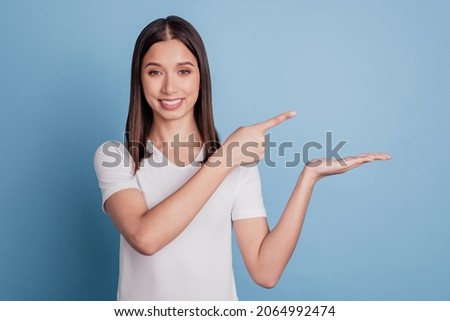 Portrait of pretty reliable lady indicate finger palm hold empty space toothy beaming smile on blue background