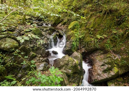 Long exposure of a waterfall on the Hoar Oak Water river flowing through the woods at Watersmeet in Exmoor National Park