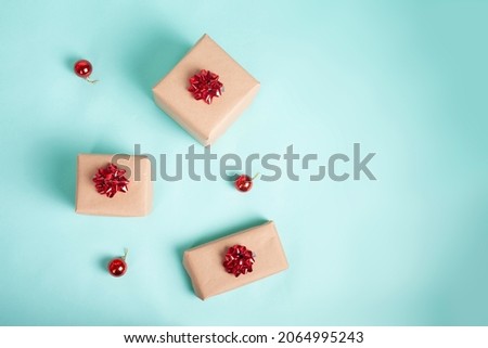 Gift boxes wrapped in kraft paper and tied with red christmas bow on a blue background