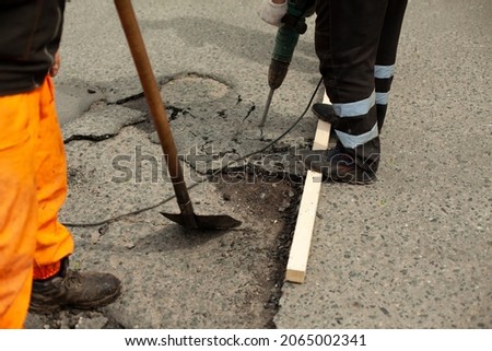 Shovel in hand. Jackhammer in operation. Workers repair the asphalt. Replacement of the road surface.