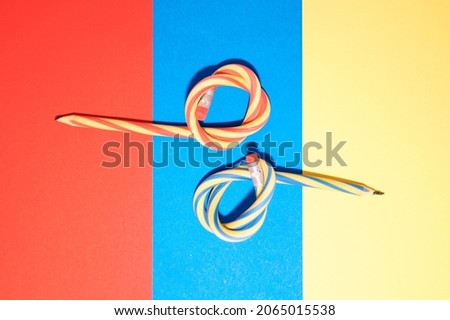 Flexible pencils on a three-color background - red, blue, yellow. Bent pencils are two-color.