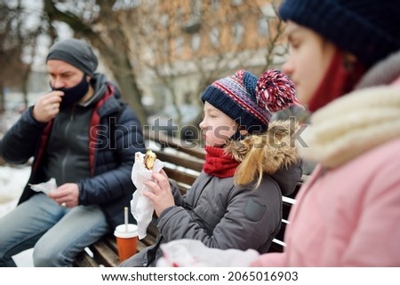 Two young sisters and their father having hot chocolate and snacks on chilly winter day at city park. Dad and kids having bonding time. Winter activities for family with kids.