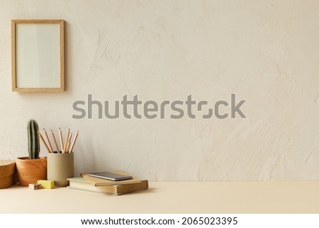 Desk with office supplies, plant, boxes, wooden frames and plaster texture wall at freelancer's home interior. Vintage style workspace.