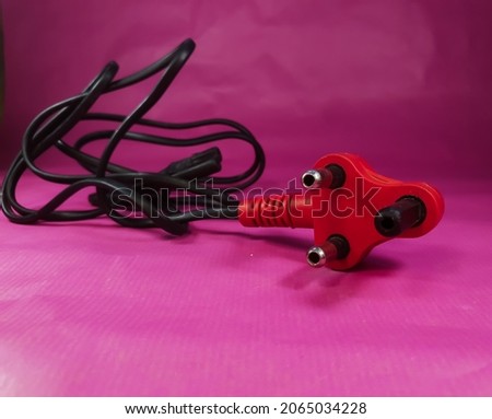 close up of a south African three point plug and cable on a pink paper backdrop