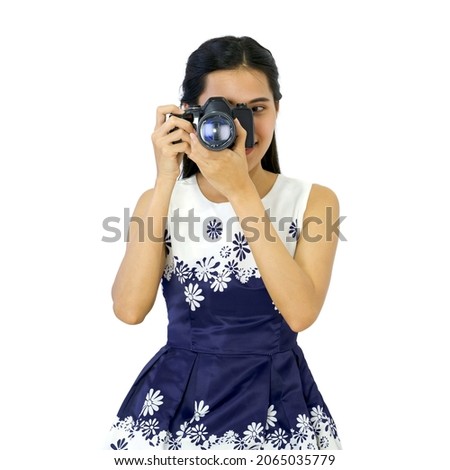 Young traveler in blue dress looks through the viewfinder while shooting with the camera.