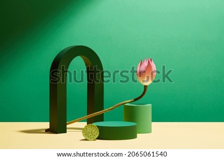 Front view of green arch circle , square podium with pink and green lotus in green background and blank space for advertising 