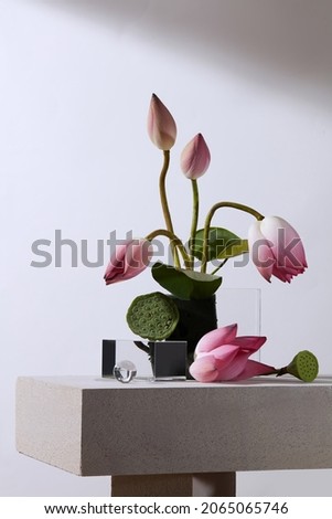 Front view of flower arrangement pink and green lotus in white background and transparent podium with blank space for advertising 