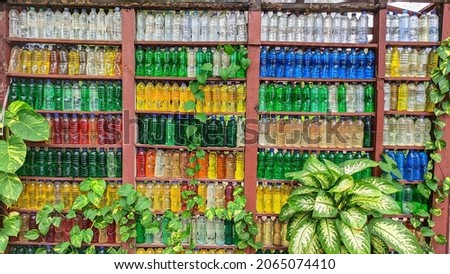a wall made of waste plastic bottles with colorful designs, pliers combined with beautiful ornamental plants.