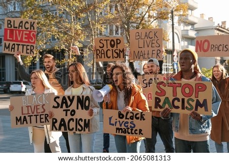 Protesters demonstrating different anti racism slogans outdoors. People holding signs with phrases Royalty-Free Stock Photo #2065081313