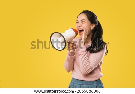 Asian woman screaming while holding megaphone with two hands making announcement Royalty-Free Stock Photo #2065086008