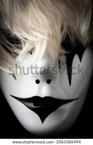 Scary mask for Halloween hand sprayed by photographer with dramatic lighting and black background