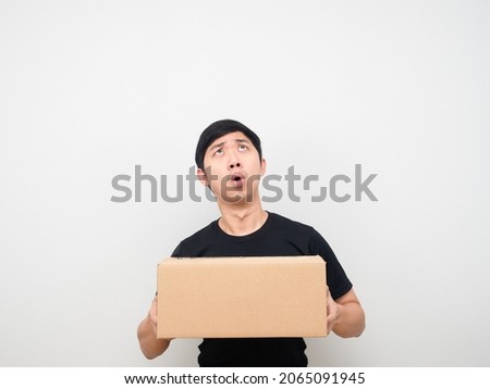 Man holding parcel box feeling amazed looking up at copy space