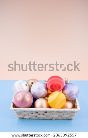Multicolored Christmas decorative balls in a wicker canister with sapce for text on a blue background