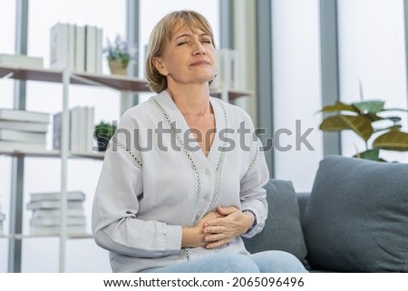 Flatulence caucasian mature adult, senior woman hand in stomach ache, suffer from food poisoning, abdominal pain and colon problem, gastritis or diarrhoea. Patient belly, abdomen or inflammation. Royalty-Free Stock Photo #2065096496