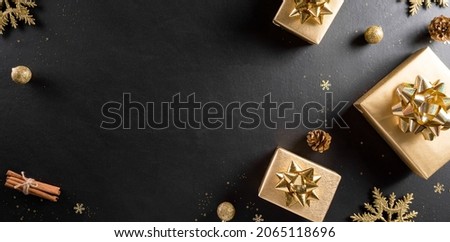 Christmas and new year background concept. Top view of Christmas gift box, pine cones, christmas ball and snowflake on black wooden background.
