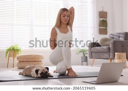 Beautiful woman with dog following online yoga class at home