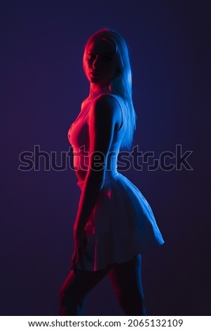 A portrait of a young Canadian woman in sportswear posing under blue and red lights in a dark studio