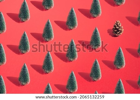 Arranged green New Year and Christmas tree with brown cone on a red pastel background. Pattern.