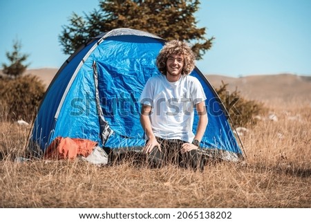 An afro teenager comes out of a mountain tent after a sleepless night. High quality photo