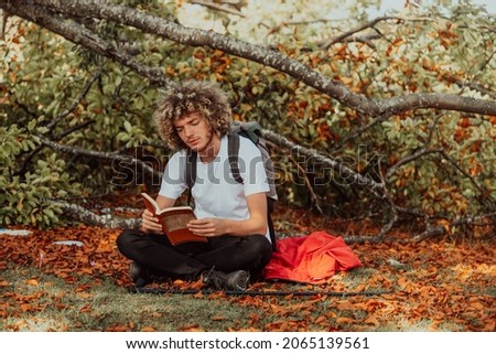 An afro teenager relaxes while reading a book while sitting in the woods in beautiful autumn weather. High quality photo